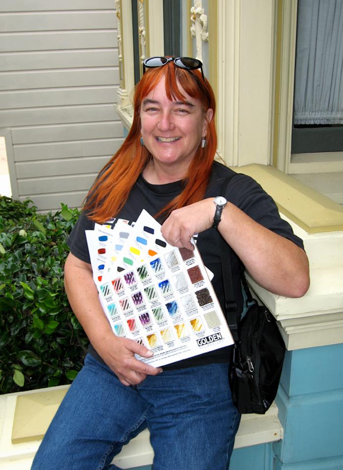 A photo of Nina showing off Golden paint swatches.